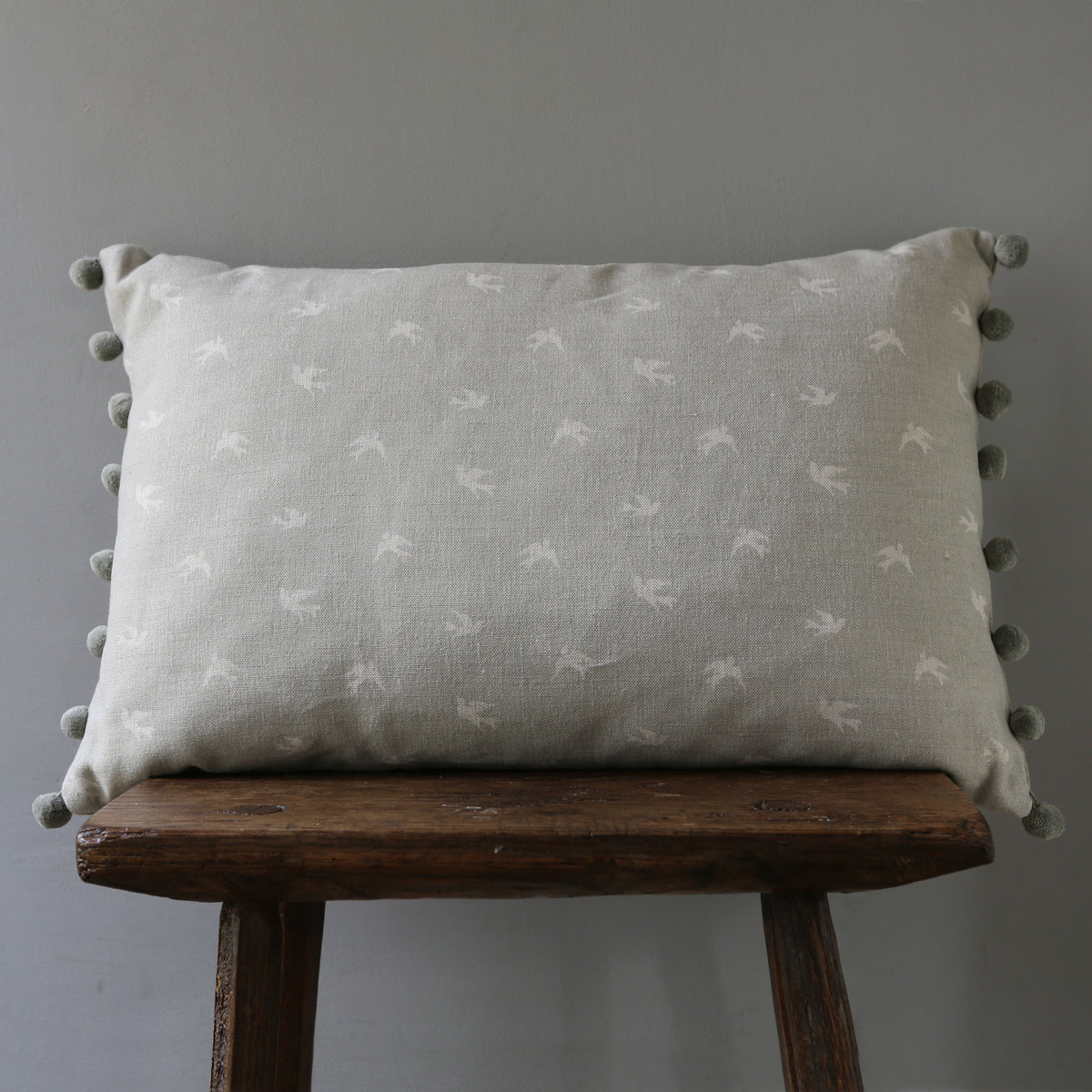 Grey cushion with outlet pom poms