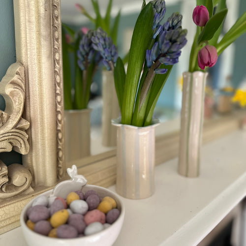 The handmade daisy stripe and scallop vase by Sea Bramble ceramics on a mantelpiece in a Easter display