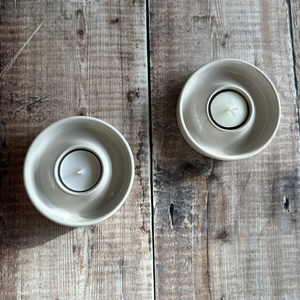 A pair of handmade candle holders in a linen glaze with tealights inside them